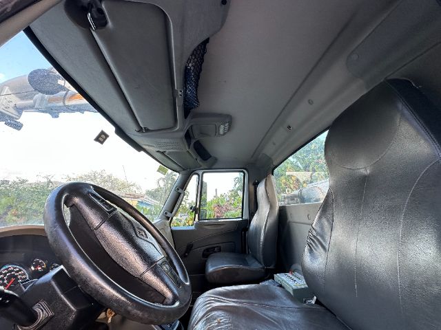 Interior of a 2016 International 7400 vacuum truck cab showing steering wheel, driver seat, and dashboard area.