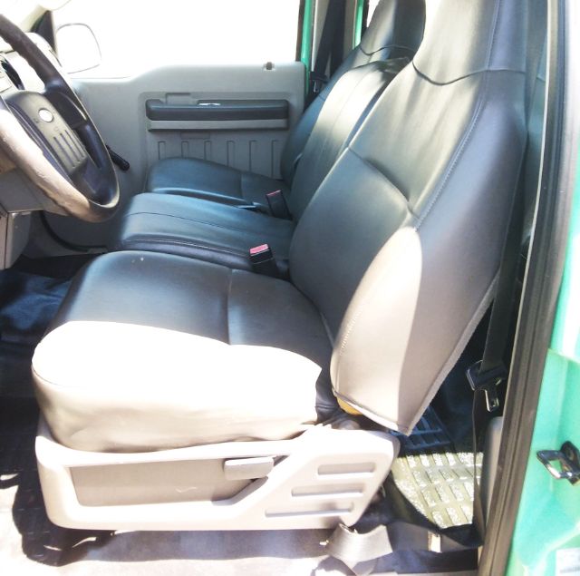 Truck interior showing front seats and part of driver area; leather seats, light gray door panel, green exterior visible.