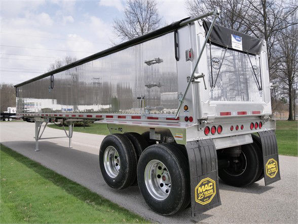 Aluminum lightweight frameless dump trailer showing polished exterior, dual rear axles, and MAC mud flaps.