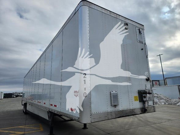Rear-side view of a silver Wabash trailer with a large white bird graphic on the side and dual rear doors.