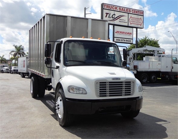 2014 Freightliner BUSINESS CLASS M2 106 chassis with chipper body, front view showing sign reading TRUCK SALES CENTER in background.