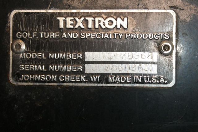Textured metal plate showing TEXTRON Golf, Turf and Specialty Products branding with Model Number and Serial Number fields, and 'Johnson Creek, WI Made in U.S.A.' inscription.