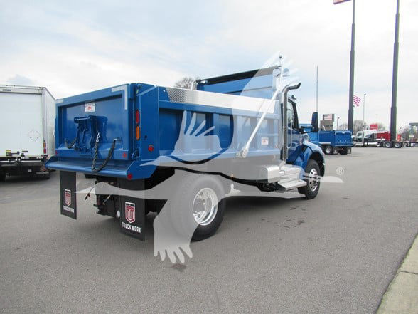 Kenworth T380 dump truck rear and side view with blue bed, black mud flaps, and chrome wheels. Blocky tailgate and hydraulic dump mechanism visible.