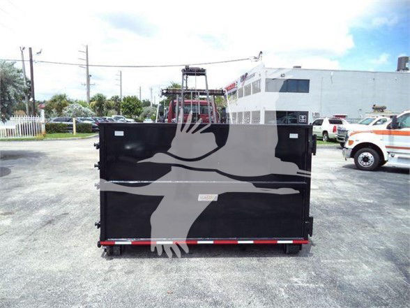 Back view of a black Freightliner refuse truck body with large gray crane and crane logo, parked in lot.