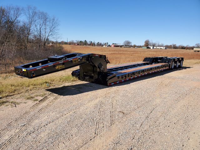Atoka trailer lowboy in an open lot showing long low-profile deck with multiple axles and a gooseneck area.