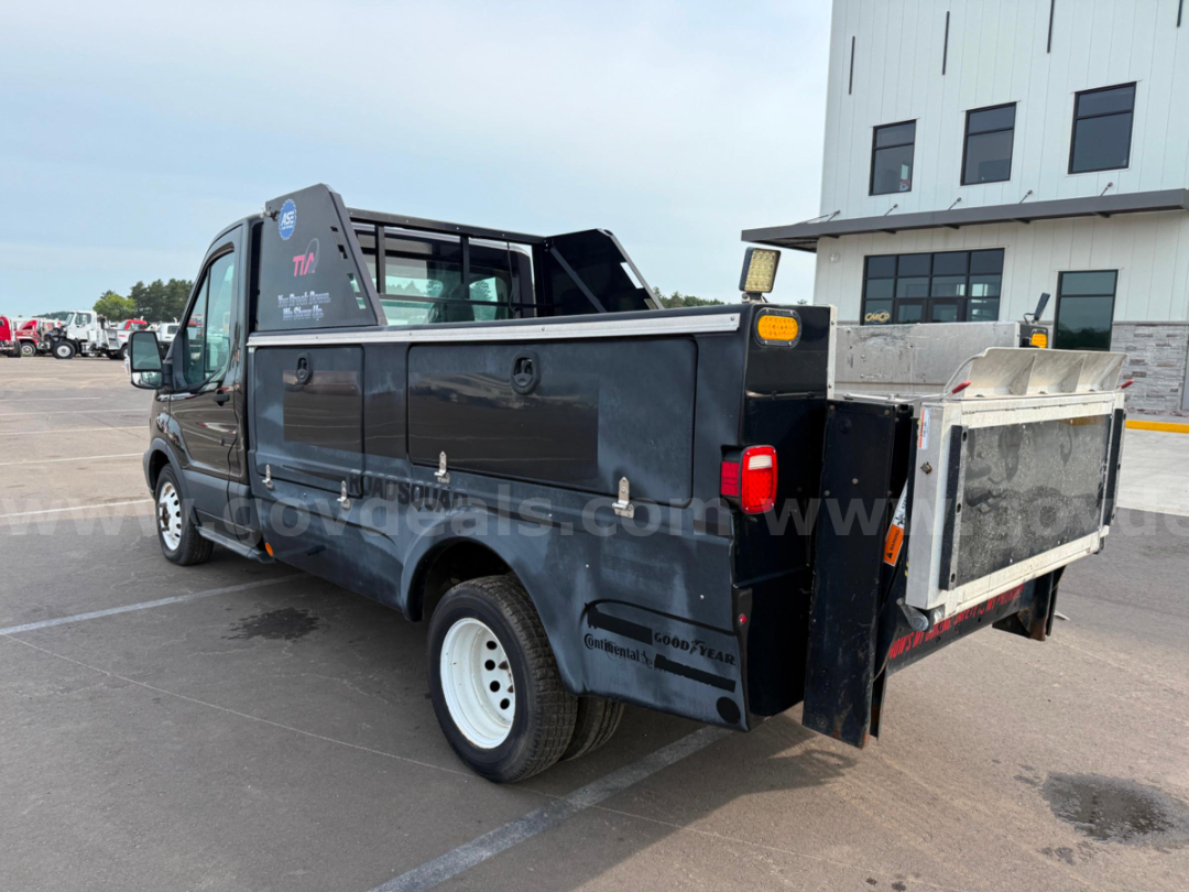 Ford Transit utility van with service bed and spare wheel, side toolboxes, and rear access ladder rack. Side decals include Goodyear and Continental brands.