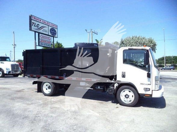 Isuzu NPR-HD truck side view with a black dump bed, white cab, and stock number sign in background.