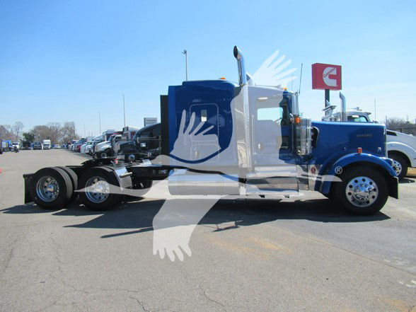 Kenworth W900L truck side view showing blue and white cab and long chassis in a dealership lot.