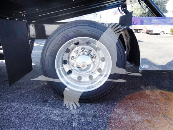 Full-size wheel of a Peterbilt 337 truck showing polished steel rim with bolts and hubcap; undercarriage frame and wheel well visible.