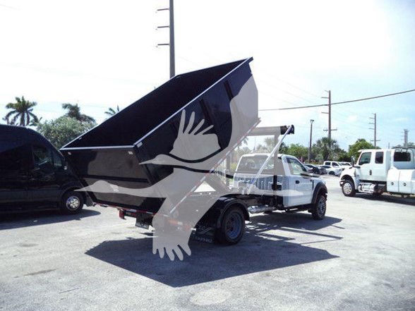 Ford F-550 dump bed truck front-left view with raised dump bed, white cab, black dump bed in raised position.