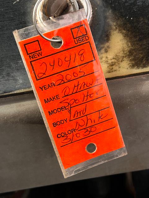 Red tag hanging from a trailer showing year 2003, make Ottawa, model H? and body Farm? with handwritten details.
