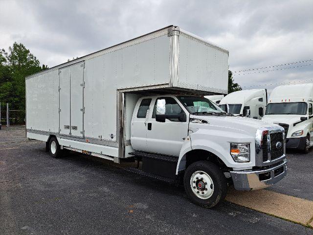 Ford F-650 box truck in service bay showing large white cargo box and cab with dual rear wheels.