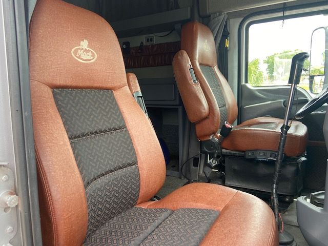 Cab interior of a 2010 Mack CXU613 with brown fabric seats and driver seat, steering wheel, and passenger seat visible.