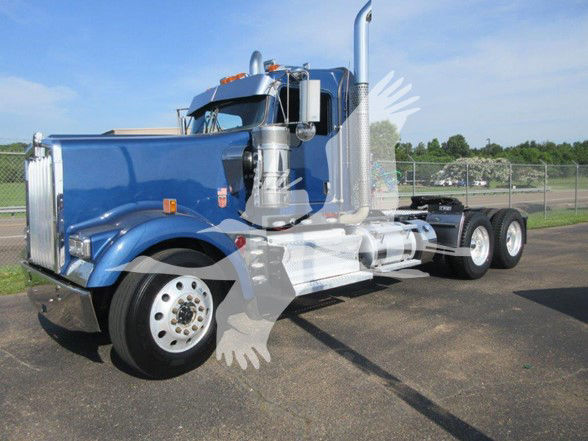 Blue 2022 Kenworth W900L conventional day cab truck on pavement, side view showing long chrome exhaust stack and dual rear axles.