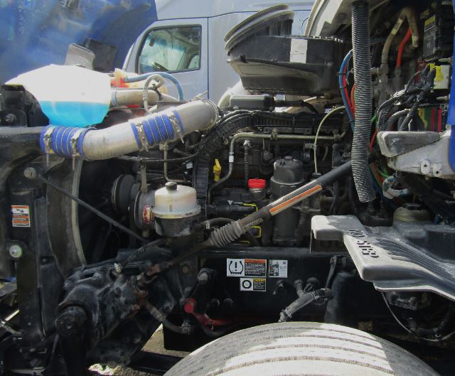 Kenworth T680 engine bay showing diesel engine, hoses, coolant reservoir, and various wiring in a cab and chassis truck.