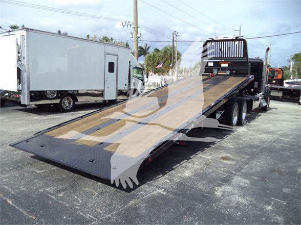 Kenworth T880 tow truck with a long low-bed tiltbed in a parking lot.