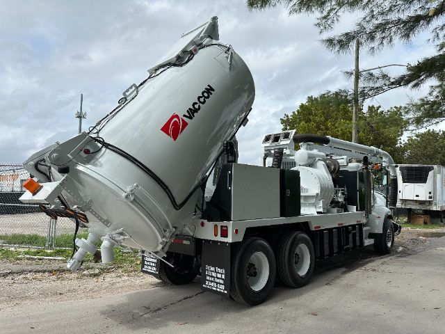 Vac-con vacuum truck with large tilted cylindrical tank and diesel engine on a white and gray chassis.