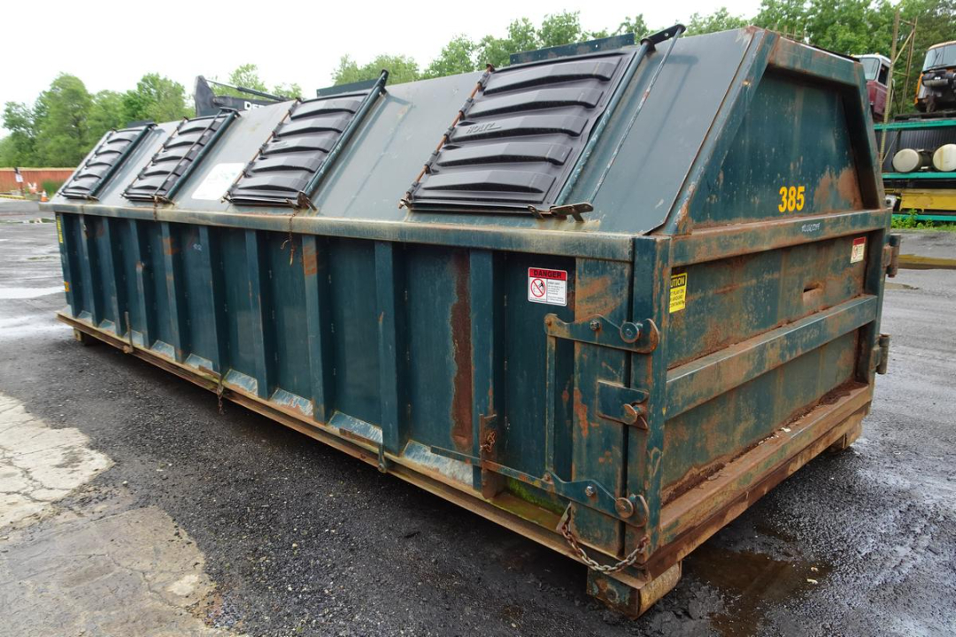 Wastequip 20 yd dumpster container showing reinforced steel walls and top access doors with black latches and caution labels.