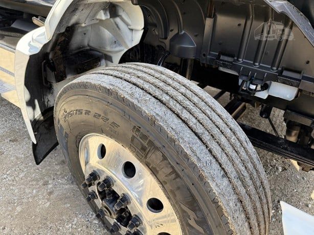 International Lonestar truck wheel and front suspension with dual axle tire, metallic wheel with lug nuts, part of front fender and engine bay visible.