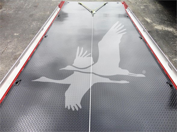 Flatbed truck deck with diamond plate surface and large white eagle graphic in flight across center; red rails on sides.