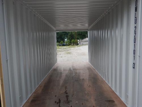 20' container interior with metal walls and wooden floor, open rear door showing outdoor area beyond.