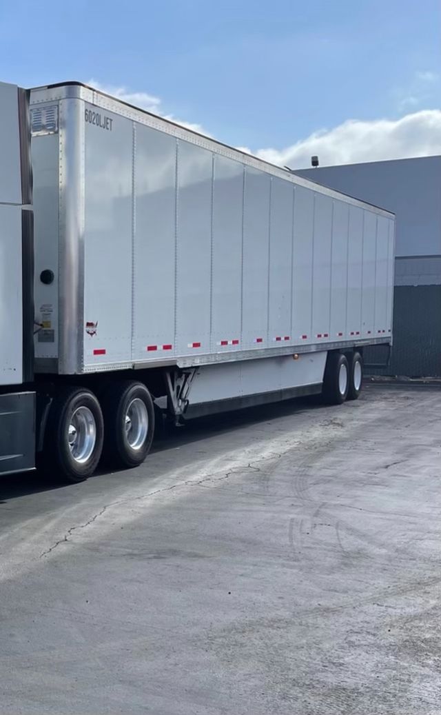2015 Wabash 53' dry van trailer attached to a semi-truck with tandem axles, silver aluminum exterior, side marker reflectors, and dual rear axles.