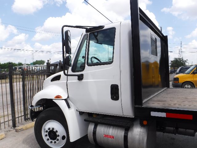 Truck cab side view of a white 2018 International 4300 with flatbed and metal fuel tank visible under door