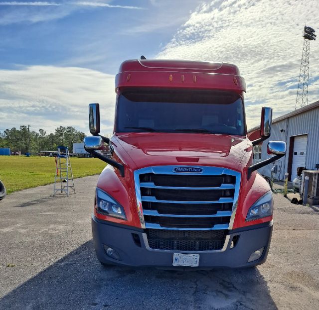 Front view of a red 2020 Freightliner Cascadia sleeper truck with large chrome grille, side mirrors, and black bumper.