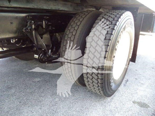 Truck rear dual wheels and suspension visible under chassis with heavy-duty tires.