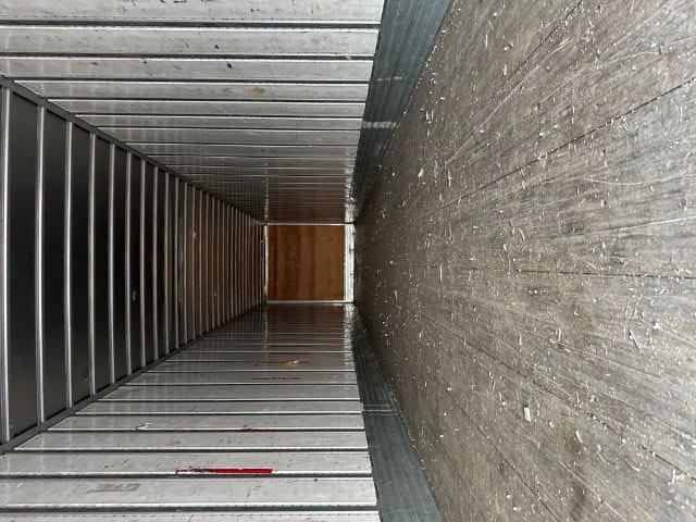 Interior of a 2015 Utility 4000DX roll door trailer showing empty cargo space with wooden floor and metal walls.