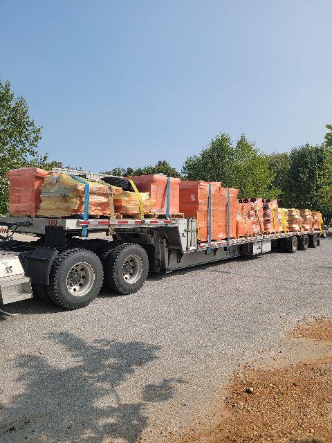 Trailer with multiple orange pallets strapped on a long flatbed trailer.
