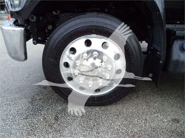 Wheel and tire assembly of a 2024 Ford F750 SD truck showing a polished multi-hole hub with lug nuts and a black tire.