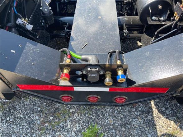 Low angle view of a 2023 Fontaine 55 ton steel roller paver lowboy rear deck showing hydraulic connections and tail lights.