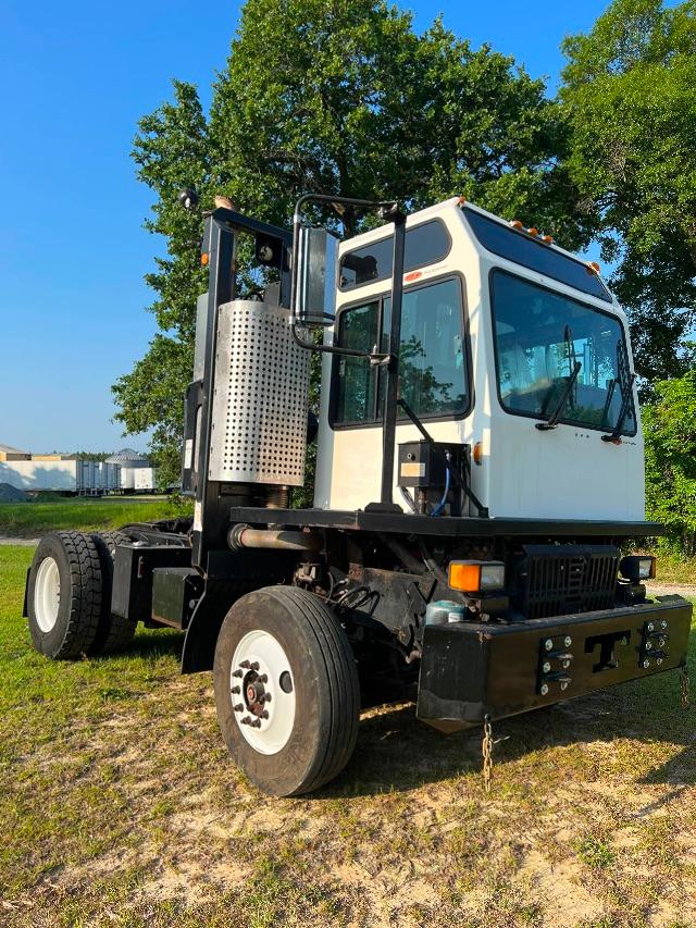 Truck cab and chassis of a 2015 Tico Prospotter in yard setting with white cab and black chassis, exposed exhaust stack, and front bumper with chains.