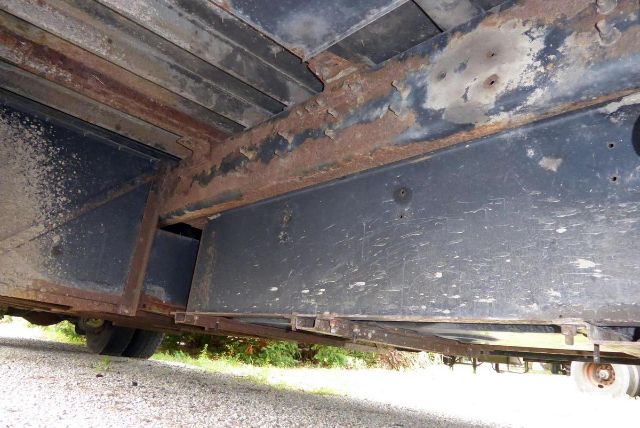 Underbody view of a Bluebird All American bus showing rusted frame rails and metal panels.
