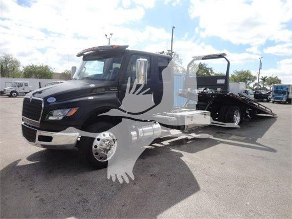Tow truck with extended flatbed, black cab, and chrome wheel, watermark of a white dove overlaying the image.