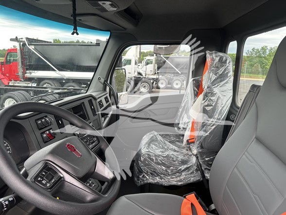 Kenworth T380 cab interior with plastic-covered seats and orange seat belts, steering wheel and dashboard visible from driver side.