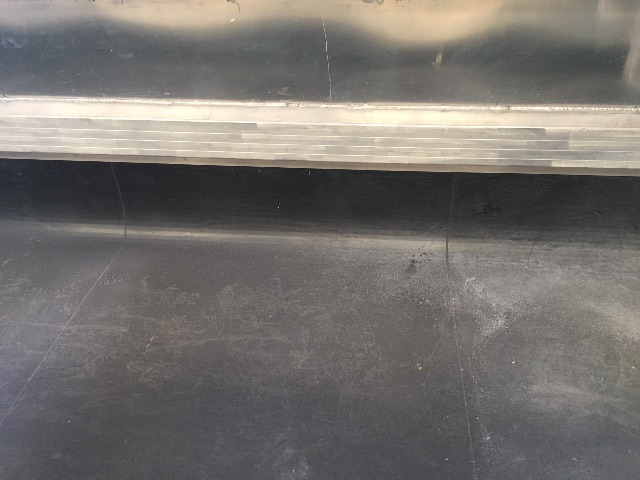 Aluminum end dump trailer interior edge showing ribbed threshold and smooth floor.