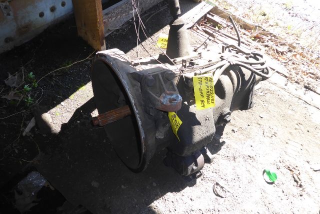 Truck transmission with drive shaft/housing and labels, showing yellow warning tags and wiring harness.