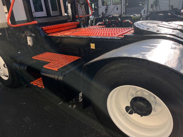 Truck or tractor unit side view showing bright orange steps and platforms, black chassis, large white wheel, fuel or battery box and step ladders.
