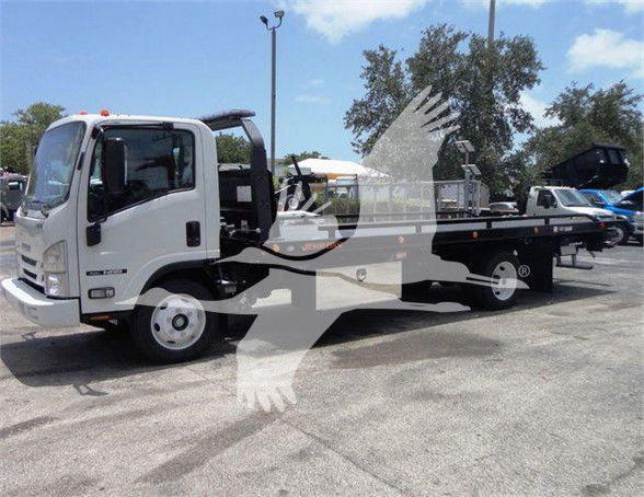 Isuzu NRR tow truck in a dealership lot with flatbed, side view showing cab and bed.