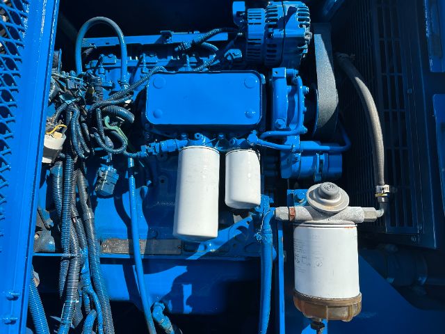 Blue Sterling L7500 engine bay with hoses, wiring, and two white cylindrical filters; large blue engine block and pump visible.