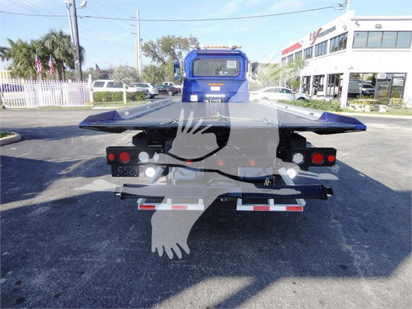 Peterbilt 337 rear view showing flatbed with multiple taillights and a blue cab in background.