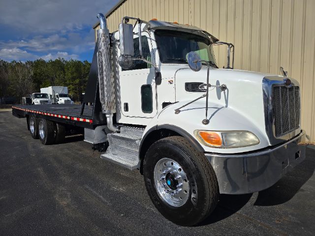 Peterbilt 348 rollback tow truck side/front view showing chrome exhaust stacks, dual mirrors, swept bumper, flatbed tow bed, and large front grille.