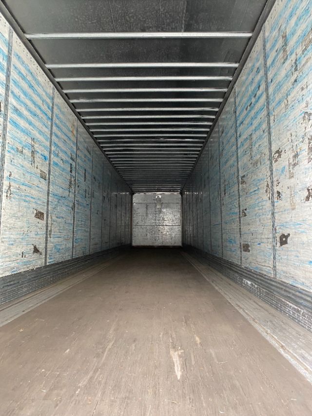 Interior of a long dry van trailer with blue Wabash Duraplate panels and metal floor, empty cargo space.
