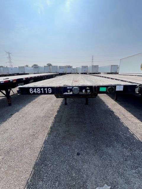 Flatbed trailer showing front center with serial/ID 648119 and coupling area; long deck with other trailers in background.