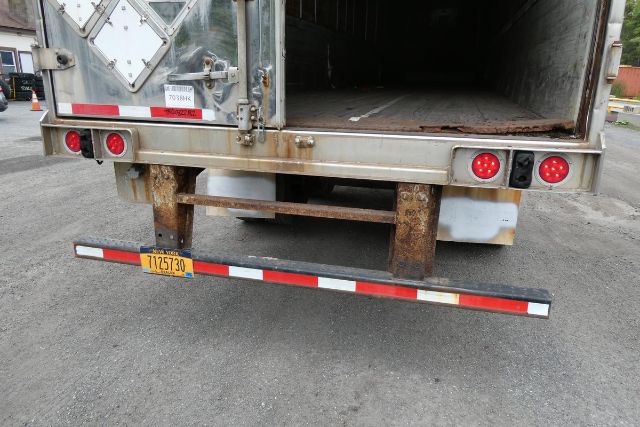 Great Dane trailer rear view showing open cargo area, rusted frame, taillights, and rear bumper with yellow license plate.
