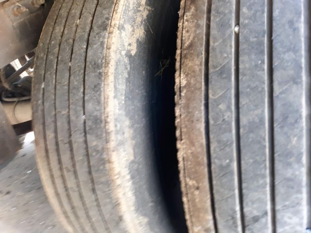 Tire tread close-up on a trailer wheel showing multiple parallel grooves and dirt along the side.