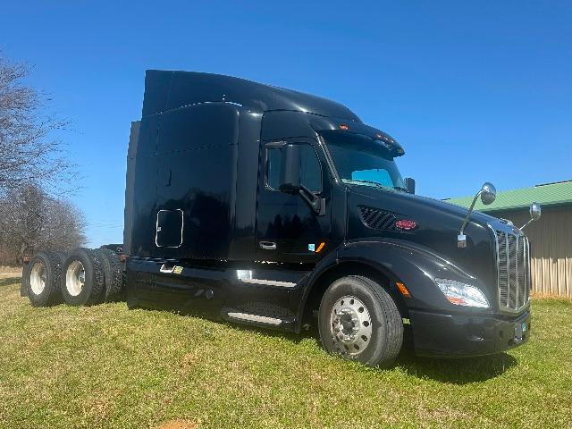 Peterbilt 579 conventional sleeper tractor in black, side view with dual rear axles, blue sky, no trailer attached.