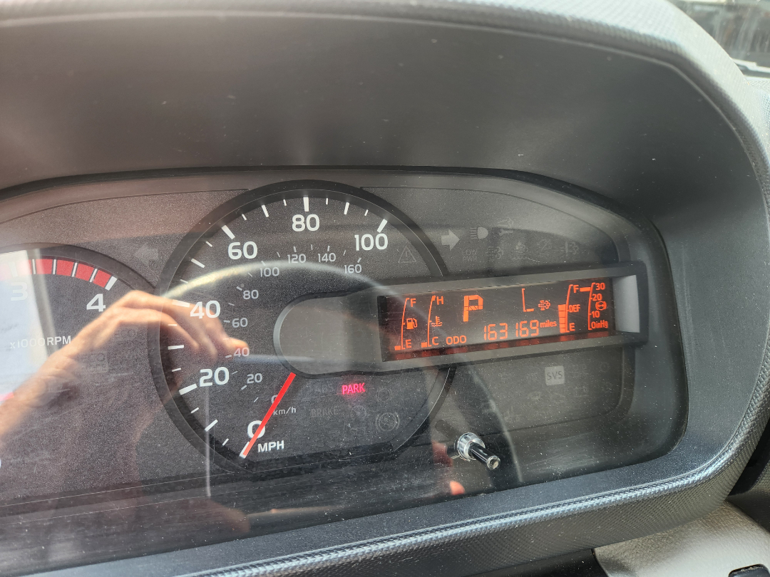 Dashboard of 2017 Hino 155 with digital display showing P gear, odometer 163,169 miles, RPM gauge, speedometer up to 100 mph, and warning indicators.